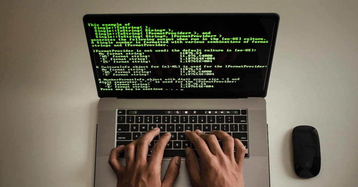 Blog header image showing fingers on a laptop keyboard, mouse and a screen showing green code.