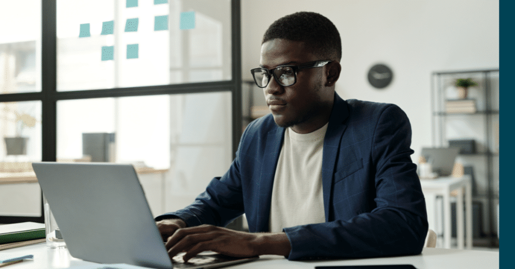 Blog header image showing a man sat at desk by a window focussed on his laptop screen