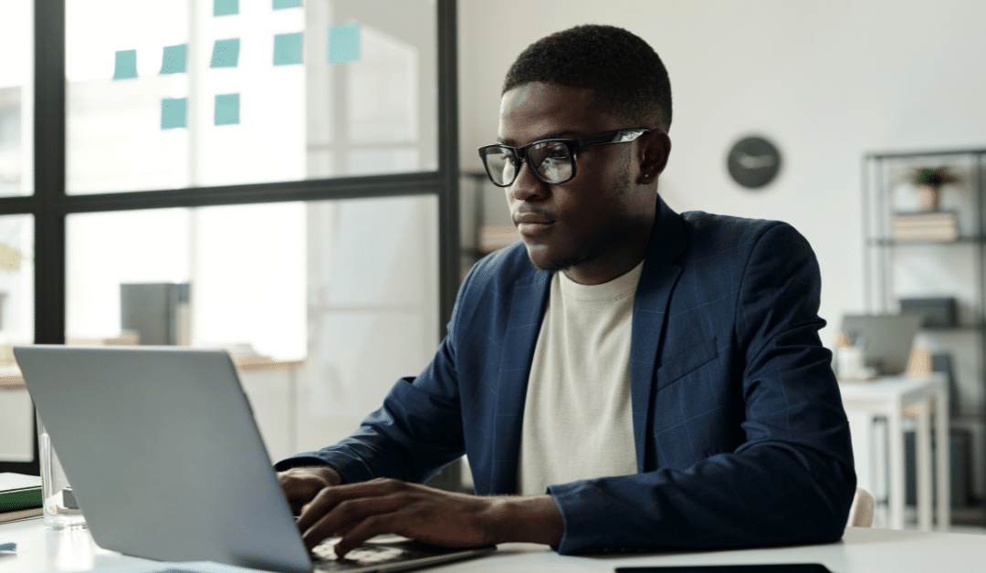 Blog header image showing a man sat at desk by a window focussed on his laptop screen